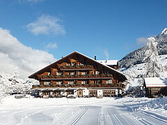 The wooden chalet of Hotel Alpenland covered in and surrounded by snow. 