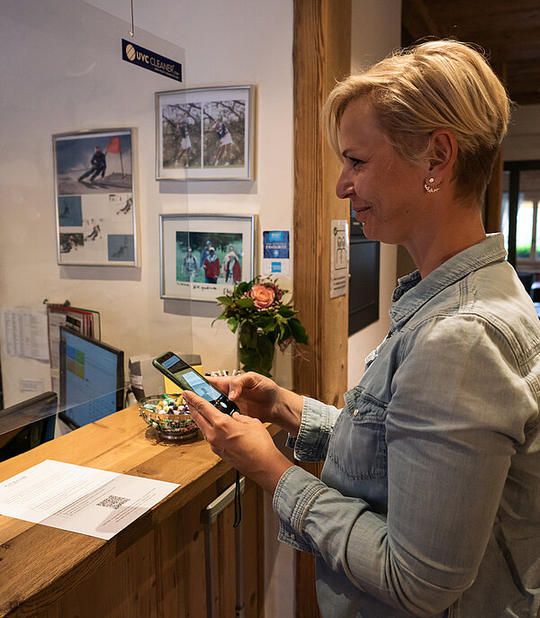 Woman checking into a hotel using her mobile phone (Gstaad Card).