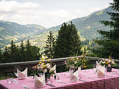 Gedeckter Tisch auf der Terrasse mit Bergen im Hintergrund
