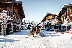 Schneebedeckte Gstaader Promenade mit Blick auf die Chalet-Häuser und Pferdekutsche