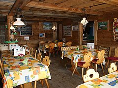 Ein gemütliches Restaurant mit Holzwänden und bunten Tischdecken. Die Tische sind ordentlich gedeckt und es gibt warme Beleuchtung.