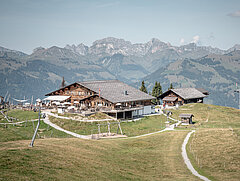 Mountain restaurant on Wispile in summer, surrounded by green meadows and overlooking the surrounding alpine mountain ranges.