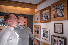 Two men look at various paintings in a gallery in Gstaad.