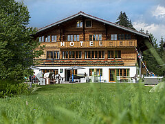Small hotel, in the foreground a green meadow.